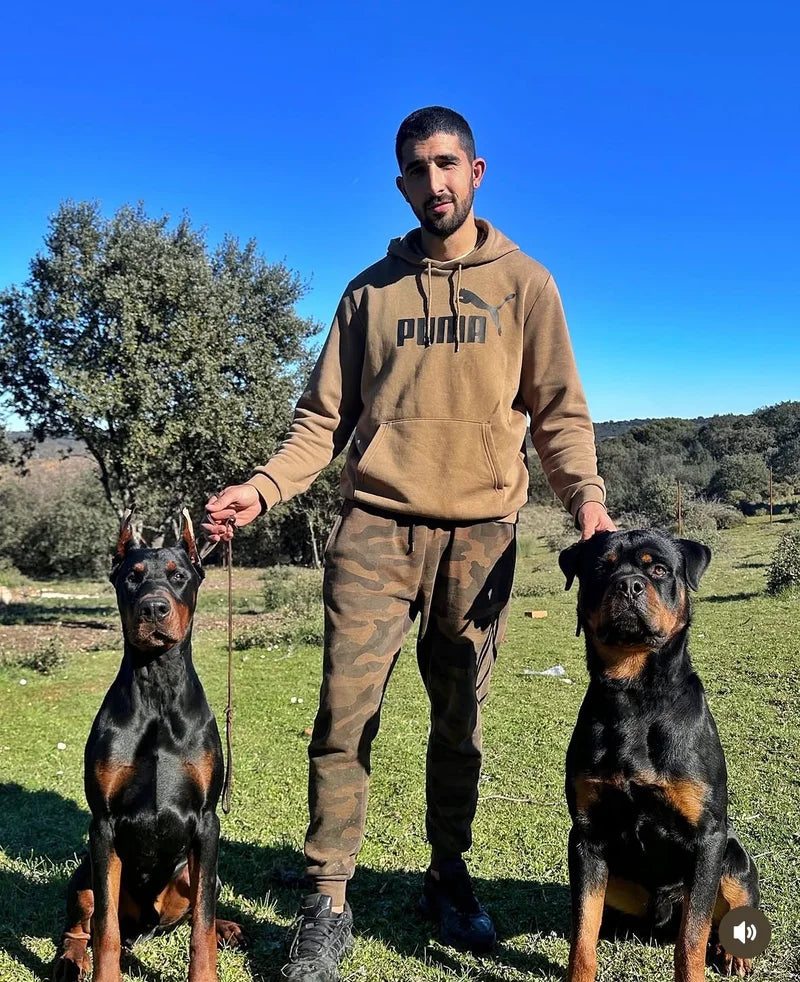 Alberto con un dóberman y un rottweiler en el campo